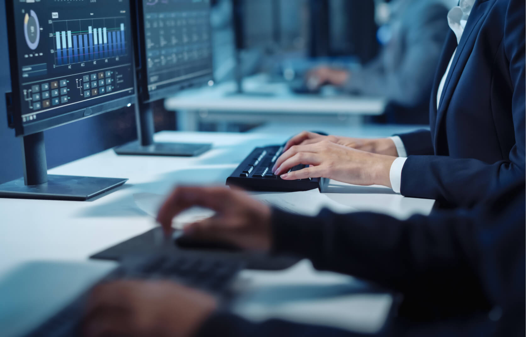 A close up of two sets of hands typing on keyboards in a cybersecurity office setting