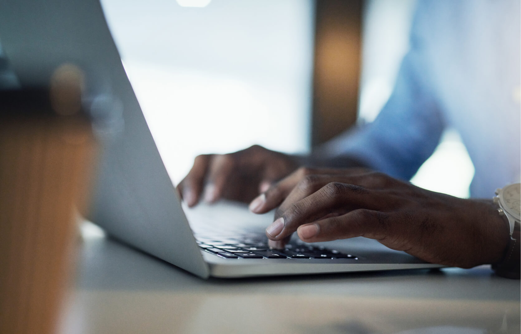 Close up of a man's hands typing on the keyboard of a laptop