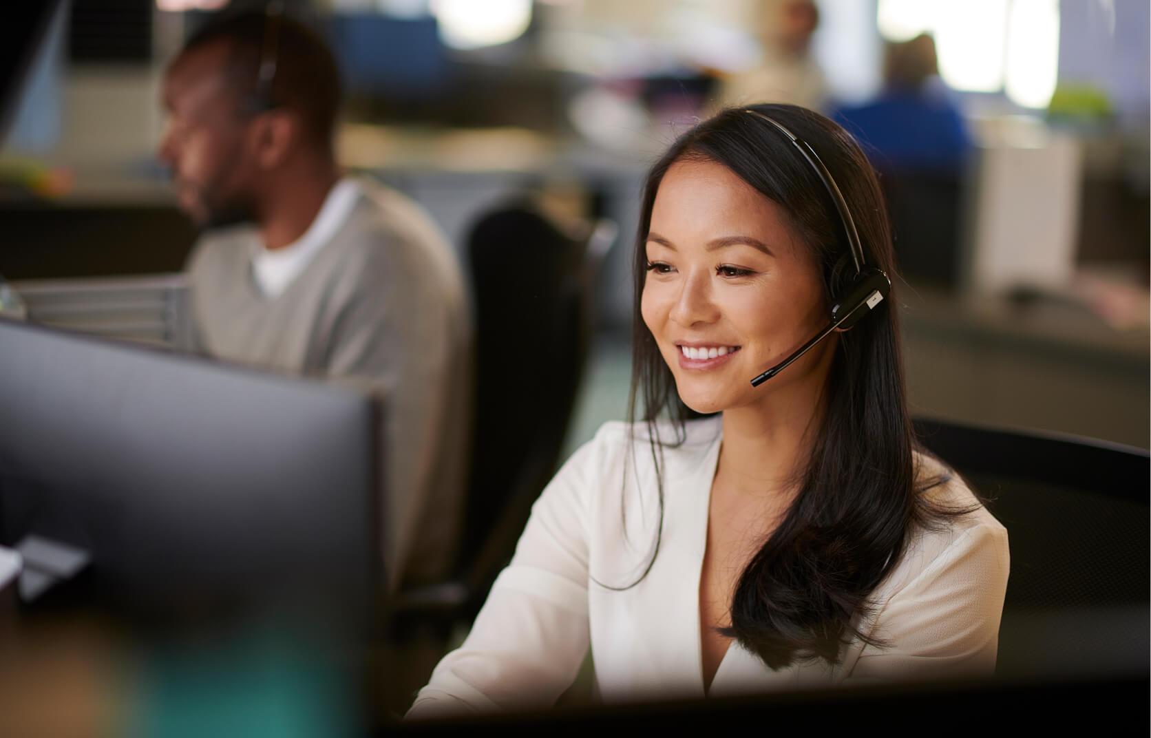 A young woman sitting at a desk with a phone headset on providing end user IT support to clients