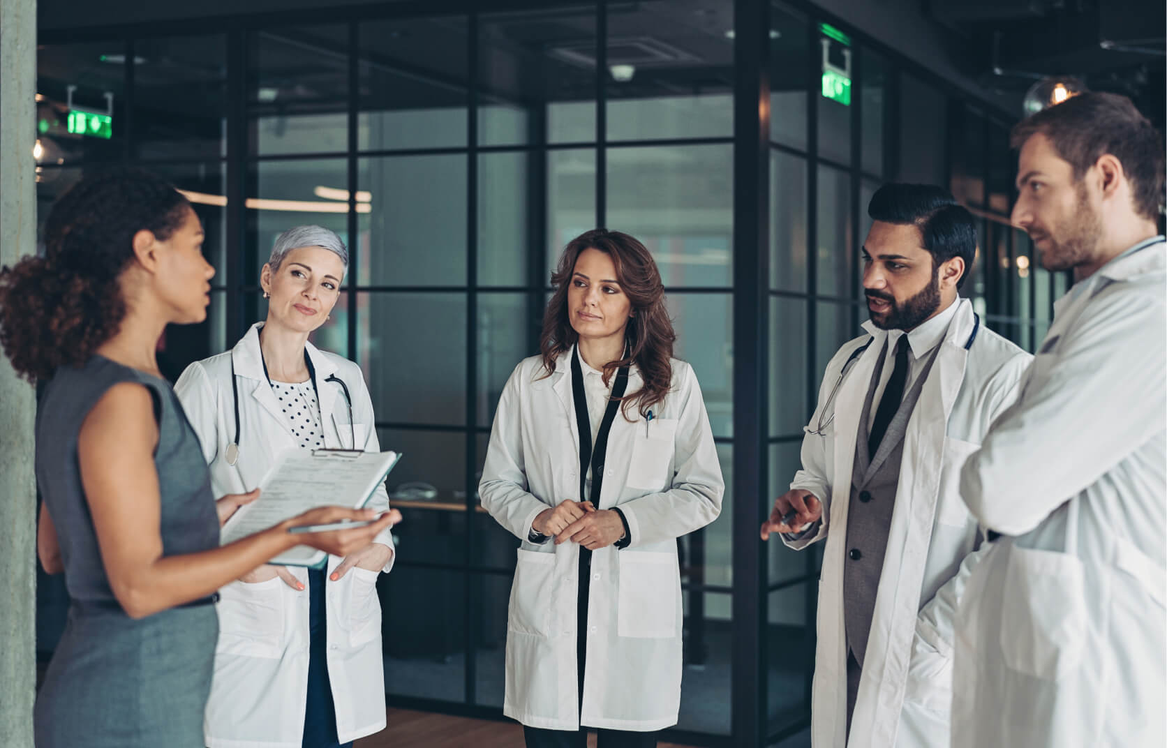 A young woman meeting with a team of medical professionals to discuss their data compliance with HIPPA regulations