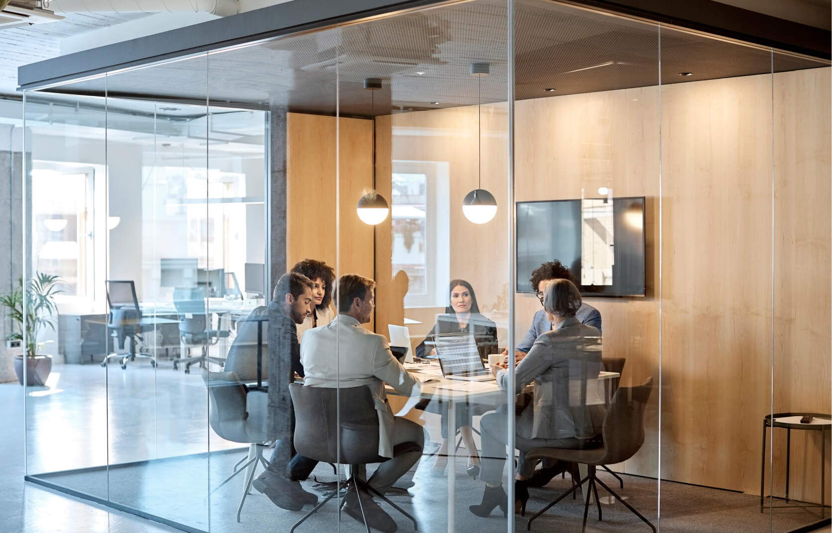 A group of men and women in a modern glass conference room discussing a cybersecurity risk assessment