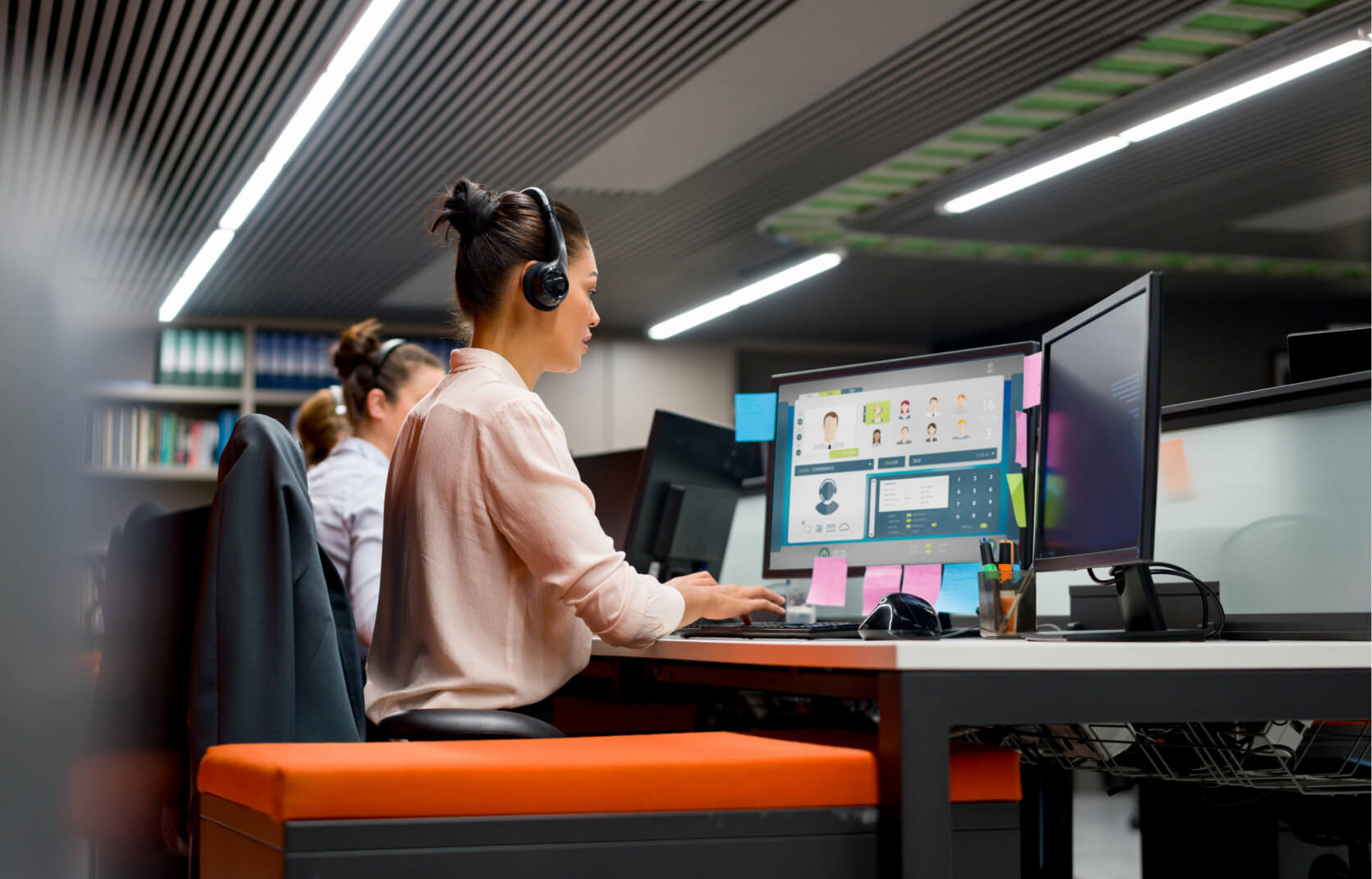 A young woman wearing headphones while working at a computer to provide managed cloud services