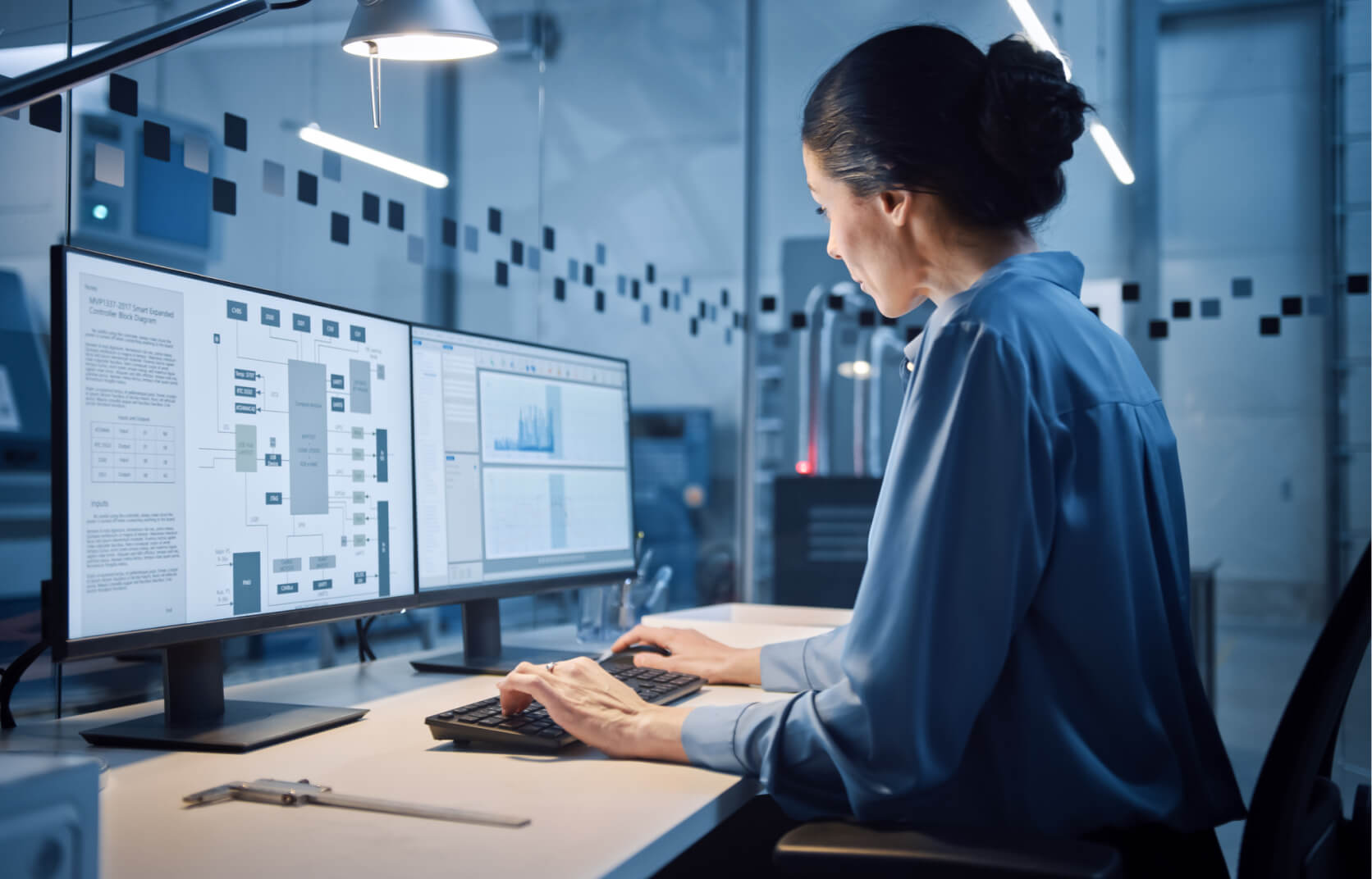 An experienced female vCISO reviewing cybersecurity policies and standards on two computer monitors