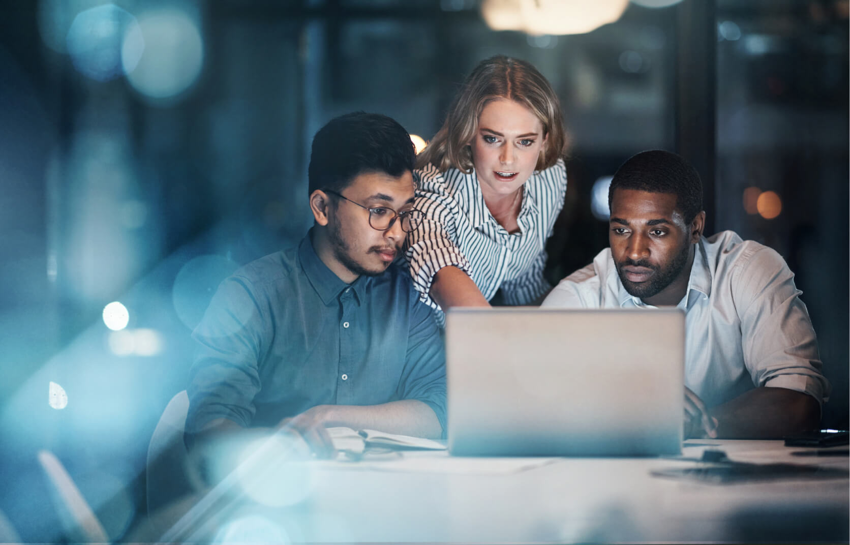 A team of cybersecurity consultants gather around a laptop to review cybersecurity regulatory frameworks