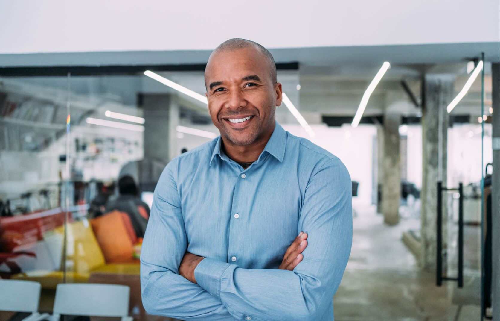A male cybersecurity expert standing with his arms crossed in a modern technology office